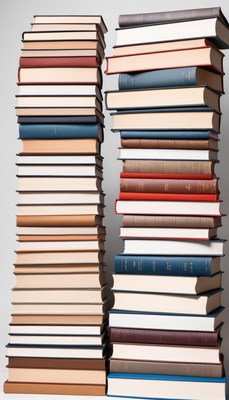 Tall stacks of books arranged neatly on a gray background
