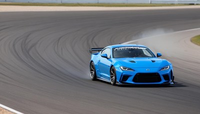 Blue sports car drifting on a racetrack during the day