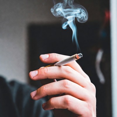 Smoking cigarette indoors with smoke rising