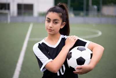 Young athlete holding soccer ball on field