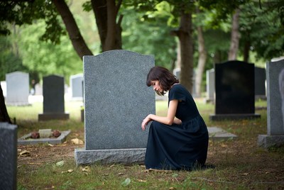 Woman mourning at a gravesite in autumn