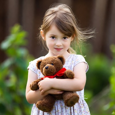 Little girl holding teddy bear outdoors