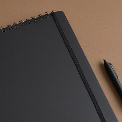 Black notebook and pen on desk