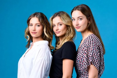 Three women posing against a blue background