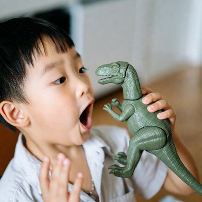 Excited boy plays with dinosaur toy