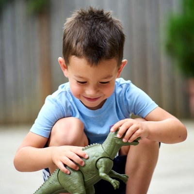 Boy playing with dinosaur toy outside