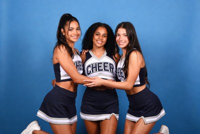 Cheerleaders posing against blue backdrop
