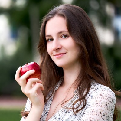 Young woman holding a red apple outdoors