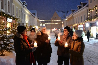 People holding candles in snowy street