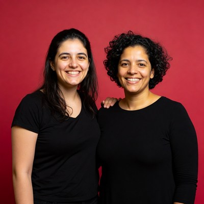 Two women smiling against a red backdrop