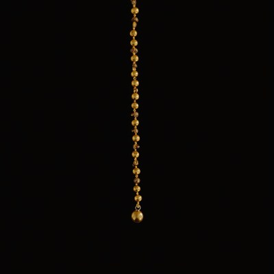 Gold necklace hanging in dark