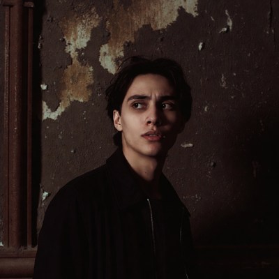 Young man in dark setting looks away