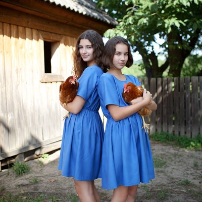 Girls holding chickens by a barn