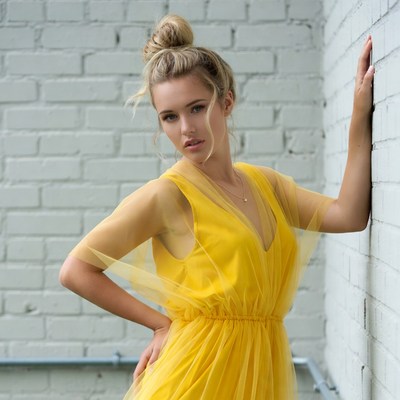 Woman in yellow dress by brick wall