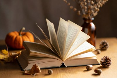 Open book with fall decorations on table