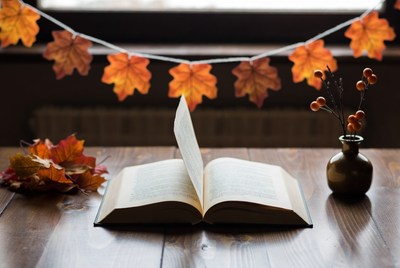 Open book on wooden table with autumn decor