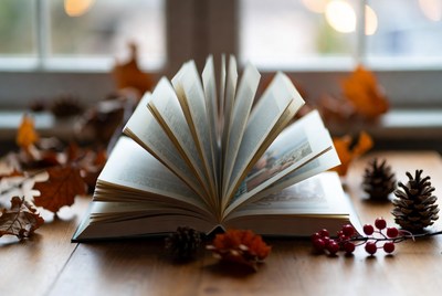 Open book on wooden table with leaves