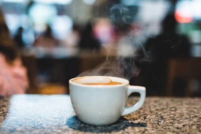 Steam rises from a cup of coffee in a cafe