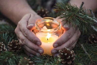 Candle held among pine branches
