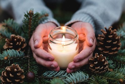 Hands hold candle in winter setting