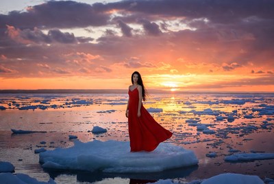 Woman stands on ice at sunset