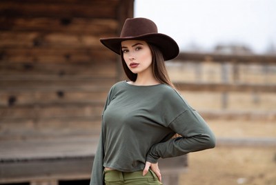 Woman poses in cowboy hat at ranch