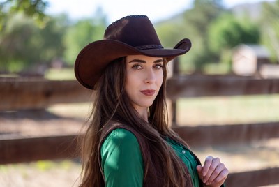 Woman poses in cowboy hat outdoors