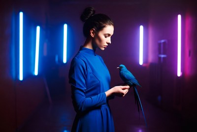 Woman with blue bird in dark room