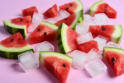 Watermelon slices and ice cubes on pink surface