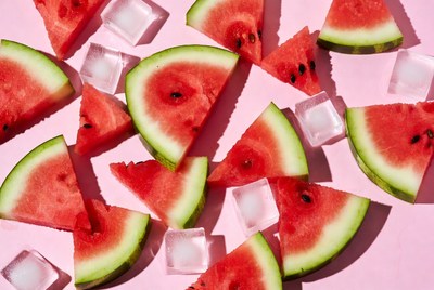 Watermelon slices with ice cubes on pink surface