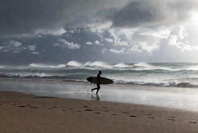 Surfer walks along stormy beach