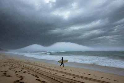 Surfer walks on beach before storm