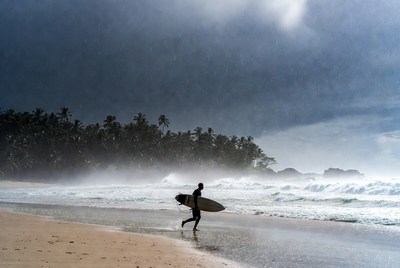 Surfer runs along wet beach