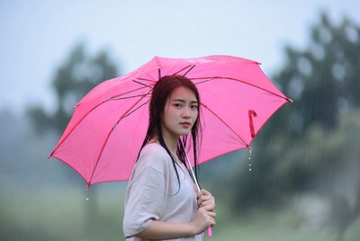 Woman holding pink umbrella in rain