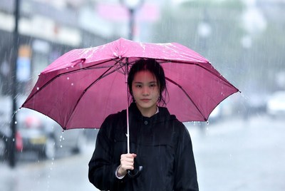 Woman walking with pink umbrella in rain