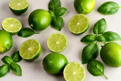Fresh limes with basil leaves on surface