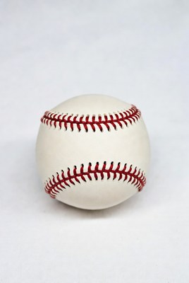 White baseball with red stitching on surface