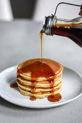 Pouring syrup over breakfast pancakes