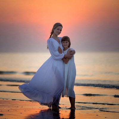 Mother and daughter on the beach at sunset