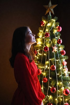 Woman next to christmas tree with lights