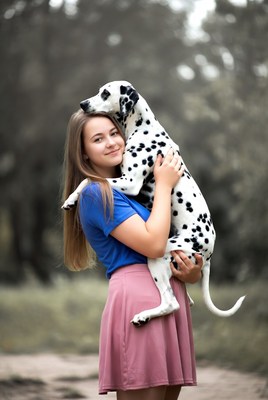 Girl holds dalmatian dog in park