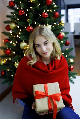 Smiling woman with gift by christmas tree