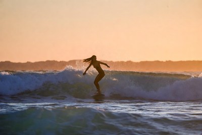Surfer dancing on ocean waves at sunset