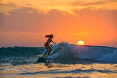 Surfer riding waves at sunset