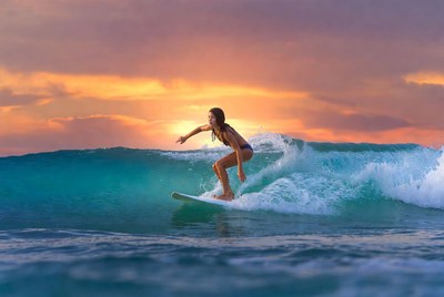 Girl surfing at sunset in ocean