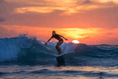 Surfer gliding on waves at sunset