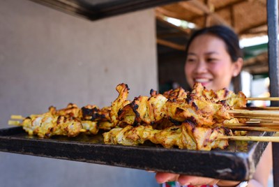 Street vendor sells grilled chicken skewers