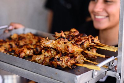 Grilling chicken skewers at street market