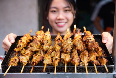 Street vendor serves grilled chicken skewers