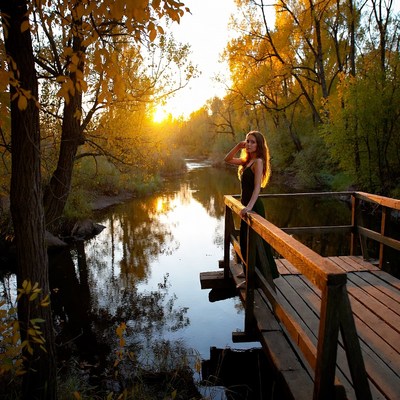 Woman on bridge at sunset near river